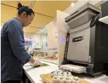  ?? The Yomiuri Shimbun ?? A sushi-making robot, right, works in a sushi restaurant in New York.