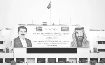  ?? — AFP photo ?? A welcoming banner featuring the portrait of Saudi Arabian Crown Prince Mohammed bin Salman (right) and chairman of the Senate of Pakistan, Sadiq Sanjrani, is displayed on the building of the Parliament House in Islamabad.