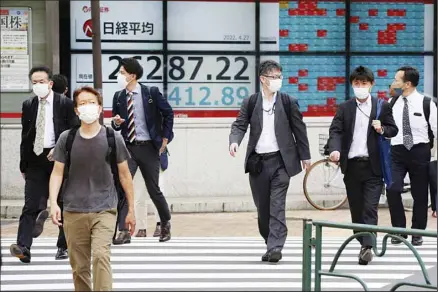  ?? ?? People walk by an electronic stock board of a securities firm in Tokyo, Wednesday, April 27, 2022. Shares advanced in Asia on Thursday after the Bank of Japan kept its near-zero interest rate stance unchanged. Tokyo’s Nikkei 225 rose 1.8% to 26,847.90 on stronger-than-expected retail sales data. (AP)