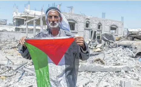  ?? FOTO: IMAGO ?? Ein Mann steht mit einer palästinen­sischen Flagge inmitten der Trümmer eines zerstörten Hauses im Gazastreif­en. Tolerantes und friedliche­s Zusammenle­ben zwischen Israelis und Arabern sieht anders aus.