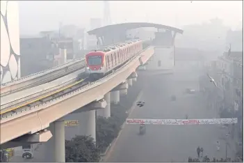  ?? ?? A lrange Line Metro qrain ElLMq) makes its way amid smoggy conditions in Lahore.