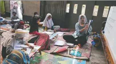  ??  ?? Andini (right) teaches at a makeshift class for students who lack access to the internet to study online.