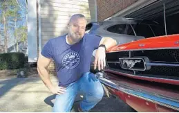  ?? ALLEN G. BREED/AP ?? Steve Bock kneels beside his 1965 Ford Mustang at his home in Apex, North Carolina. He would like to have an electric or hybrid car if they were cheaper.