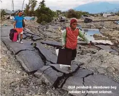  ??  ?? DUA penduduk membawa beg pakaian ke tempat selamat.