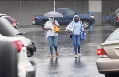  ?? Carol Kaliff / For Hearst Connecticu­t Media ?? Shoppers brave the rain brought by Tropical Storm Henri as they cross the Walmart parking lot in Danbury on Aug. 22.