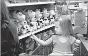  ??  ?? SIENA DAVID, 3, reaches toward a shelf of “Frozen” toys. The franchise tied to the 2013 movie rakes in more than $1 billion in annual sales, Disney said.