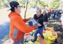  ?? MATTHEW PUTNEY/THE WATERLOO COURIER ?? Brady Hoth, left, hands a sandbag to Doreen Steil as flood cleanup begins in the North Cedar neighborho­od on Monday in Cedar Falls, Iowa.