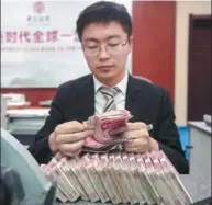  ?? ZHANG YUN / CHINA NEWS SERVICE ?? A cashier counts currency at a bank outlet in Taiyuan, capital of Shanxi province.