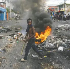  ?? RICHARD PIERRIN / AFP VIA GETTY IMAGES ?? A mans walks past a burning barricade in Port-au-prince, Haiti. The island country is in chaos as lawless criminal gangs roam the country unopposed, wreaking
havoc on impoverish­ed citizens.