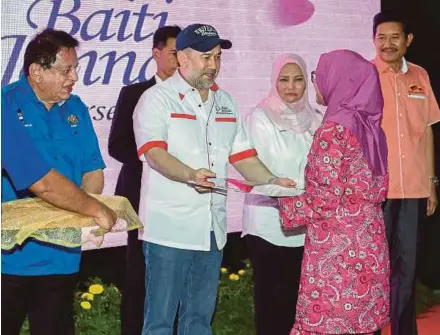  ?? BERNAMA PIC ?? Yang di-Pertuan Agong Sultan Muhammad V presenting a replica of a house key to a recipient of the People’s Housing Project and Public Housing programme in Kuala Lumpur yesterday. With them is Federal Territorie­s Minister Datuk Seri Tengku Adnan Tengku...