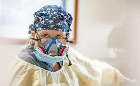  ?? Alexandra Wimley/Post-Gazette photos ?? Melinda Provance, a nurse in the intensive care unit, helps a doctor perform a procedure on a patient who has COVID-19 on March 5 at Uniontown Hospital.