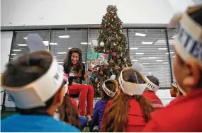  ??  ?? Lieder Elementary Principal Karen Stockton reads a Christmas story to first-graders in the Cy-Fair school’s library. The Merry Christmas Texas Project works to educate school officials and parents about the legal right to put up Christiant­hemed...