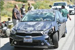  ?? Dan Watson/The Signal ?? The occupants of a Kia four-door sedan stand by the guard rail after a crash on Highway 14 on the northbound lanes near Newhall Avenue on Friday.