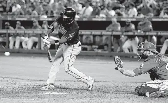  ?? Associated Press ?? Cleveland Indians’ Abraham Almonte hits an RBI single in front of Texas Rangers catcher Jonathan Lucroy during the ninth inning Monday in Arlington, Texas.