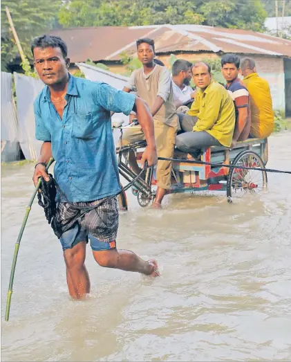 ?? Inset: People use a makeshift raft to move on a flooded area in Gaibandha, Bangladesh on Thursday. ?? People move along a flooded road in Gaibandha, Bangladesh on Thursday. Pictures: REUTERS/Stringer