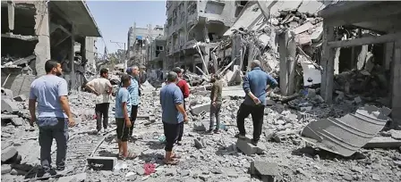  ?? (Anadolu Agency) ?? Palestinia­ns inspect the destroyed buildings after the Israeli attack on the Bureij refugee camp as Israeli attacks continue in Gaza City, Gaza on Monday