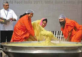  ?? Associated Press photo ?? Indian yoga guru Baba Ramdev, right, Indian Minister for Food Processing Industry Harsimrat Kaur Badal, centre, and her junior minister Sadhvi Niranjan Jyoti, second left, stir "Khichdi" at World Food India exhibition in New Delhi, India, Saturday....