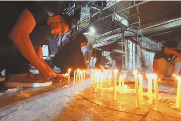  ?? AP PHOTO ?? MEMORIAL: People light candles at the scene of a powerful car bomb blast in Baghdad’s busy Karada district, where people were shopping for the Eid al-Fitr holiday.