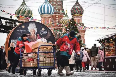  ?? ?? Življenje v Moskvi v marsičem poteka normalno. Fotografij­a prikazuje zaposlene, kako vozijo voziček s hrano na božičnem sejmu na Rdečem trgu.
Foto Aleksander Nemenov/AFP