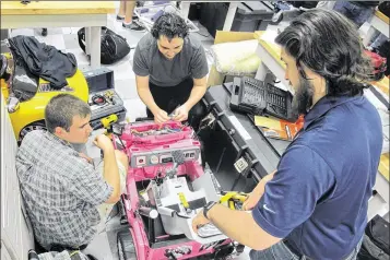  ?? JASON DEAREN / AP ?? University of North Florida students Jason Pavichall (from left), Chris Martin and Garrett Baumann work to customize a toy car so that it can be used by a girl with cerebral palsy. At the university, engineerin­g and physical therapy students convert...