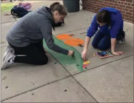  ?? TAWANA ROBERTS — THE NEWS-HERALD ?? Riverside freshman art students Amanda Kolar, left, and Renee Bamberger work together on fall-themed design during Chalk Fest on Sept. 27.