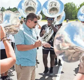  ??  ?? Colliervil­le High School director of bands James Barnes gathers marching band members during practice Aug. 31.