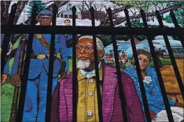  ?? CHARLES KRUPA — THE ASSOCIATED PRESS ?? Past Amherst, Mass.-area residents Henry Jackson, center, Lt. Frazar Stearns, left, and Anna Reed GoodKin, right, are featured on the Amherst Community History Mural in Amherst, Mass., Friday. The mural is seen through a fence.