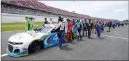  ?? JOHN BAZEMORE — THE ASSOCIATED PRESS ?? NASCAR drivers Kyle Busch, left, and Corey LaJoie, right, join other drivers and crews as they push the car of Bubba Wallace to the front of the field prior to the start of the NASCAR Cup Series auto race at the Talladega Superspeed­way in Talladega Ala., on June 22.