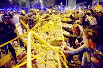  ??  ?? Protesters try to break a security barrier as they gather in front of the Spanish Govenment’s local office in Girona. — AFP photo