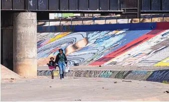  ?? ROBERTO E. ROSALES/JOURNAL ?? A Haitian mother and daughter walk toward the border wall as they successful­ly cross into the United States after crossing the Rio Grande from Ciudad Juárez, Mexico, into El Paso, Texas, in late April.