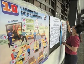  ?? ?? All set: an election worker putting up posters on voting guidelines at a polling station at SJK(C) Chung Hua No.3 in Kuching. — Zulazhar Sheblee/the Star