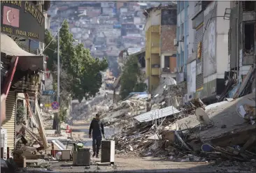  ?? PHOTOS BY UNAL CAM — THE ASSOCIATED PRESS ?? A man walks past destroyed buildings in Antakya, southeaste­rn Turkey.