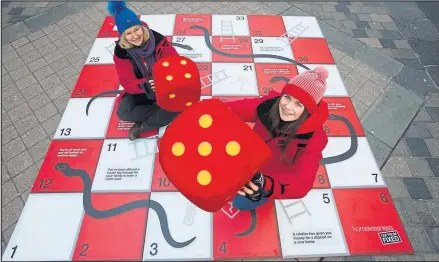  ??  ?? Vikki Skelton and Izzy Gaughan, of Shelter Scotland, play the giant snakes and ladders-style board game, and below, Alison Watson