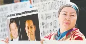  ?? JASON REDMOND / AFP / GETTY IMAGES FILES ?? A protester holds a photo of the Canadian detainees at a May court appearance for Huawei CFO Meng Wanzhou.