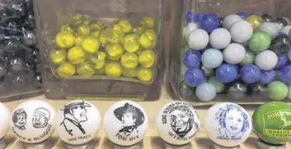  ?? ROSALIE MACEACHERN ?? Peltier style marbles display iconic images and trademarks such as superheroe­s Batman and Robin, Flintstone­s characters Fred and Barney and the John Deere farm machinery company.