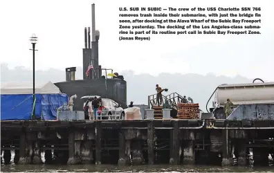  ??  ?? U.S. SUB IN SUBIC — The crew of the USS Charlotte SSN 766 removes trash inside their submarine, with just the bridge fin seen, after docking at the Alava Wharf of the Subic Bay Freeport Zone yesterday. The docking of the Los Angeles-class submarine is part of its routine port call in Subic Bay Freeport Zone. (Jonas Reyes)