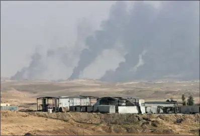  ??  ?? OIL FIELD: In this Oct. 24 photo, smoke rises as Iraqi security forces and allied Popular Mobilizati­on Forces shell Islamic State group positions at an oil field outside Beiji, some 250 kilometers (155 miles) north of Baghdad, Iraq. The United States...