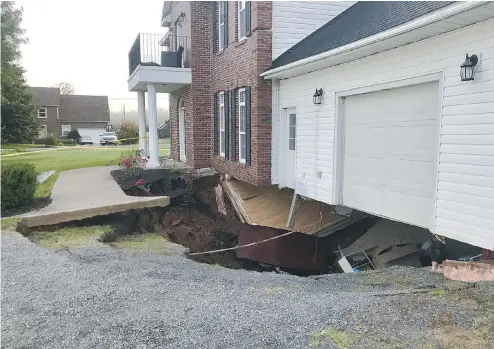  ??  ?? A sinkhole appeared under this Falmouth, N.S., house on Sunday. Officials say the family is safe, but the building is expected to collapse soon.