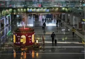  ?? ANDY WONG — THE ASSOCIATED PRESS ?? A handful of passengers walk by a Lunar New Year decoration on display at the departure hall of the Beijing Capital Internatio­nal Airport last week in Beijing. Amid fears of new variants of the virus, new restrictio­ns on movement have hit just as people start to look ahead to what is usually a busy time of year for travel.