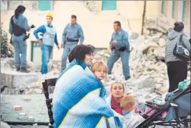  ?? AFP ?? Victims sit among the rubble of a house in central Italy.