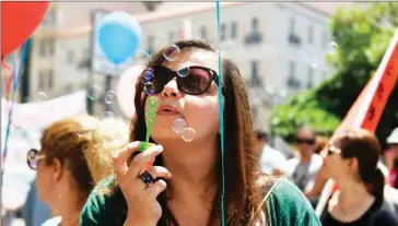  ?? LOUISA GOULIAMAKI/AFP ?? A municipal employee blows soap bubbles in central Athens on May 22 during a 48-hour strike. Hopes are high that austerity cuts will secure debt relief by EU-IMF creditors.