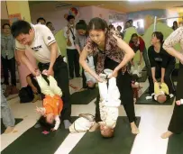  ?? AFP ?? Chinese parents perform stretching exercises with their babies at a centre in Xiamen, China’s Fujian province. —