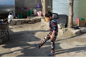  ?? — AFP photos by Noorullah Shirzada ?? Murtaza Ahmadi, a supporter of Argentine footballer Lionel Messi, playing outside his home in Kabul. (Right) Murtaza kicking stones outside his home.