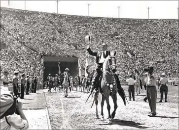  ?? Los Angeles Times ?? THEN-SHERIFF Eugene Biscailuz waves to the crowd at a rodeo at the Memorial Coliseum in 1956. Sheriff Alex Villanueva recently announced that cowboy hats were approved apparel for the department.