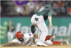  ?? RONALD MARTINEZ/GETTY IMAGES ?? Rougned Odor of the Rangers steals second in the seventh inning Monday as the A’s Jed Lowrie applies a late tag. Odor was stranded when Elvis Andrus struck out to end the inning.