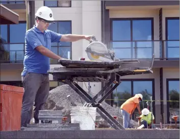  ??  ?? Hilltop Contractor­s Manager Dimitri Matveev cuts a basalt cap for the pool bar Friday morning.