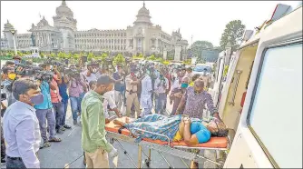  ?? PTI ?? Family members bring a Covid-19 positive patient in front of Vidhana Soudha to protest as they did not get a bed at a government hospital in Bengaluru on Thursday.