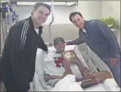  ?? ASSOCIATED PRESS ?? In this photo released by Louisville, injured guard Kevin Ware holds the NCAA Regional Championsh­ip trophy flanked by coach Rick Pitino and his son Richard Pitino.