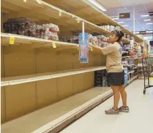  ?? AP PHOTO ?? SOLD OUT: A woman takes water from largely empty shelves at a Honolulu supermarke­t yesterday.