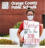  ?? JOE BURBANK/ORLANDO SENTINEL VIA AP ?? Rachel Bardes holds a sign in front of the Orange County Public Schools headquarte­rs as teachers protest with a car parade around the administra­tion center in downtown Orlando, Fla., earlier this month.